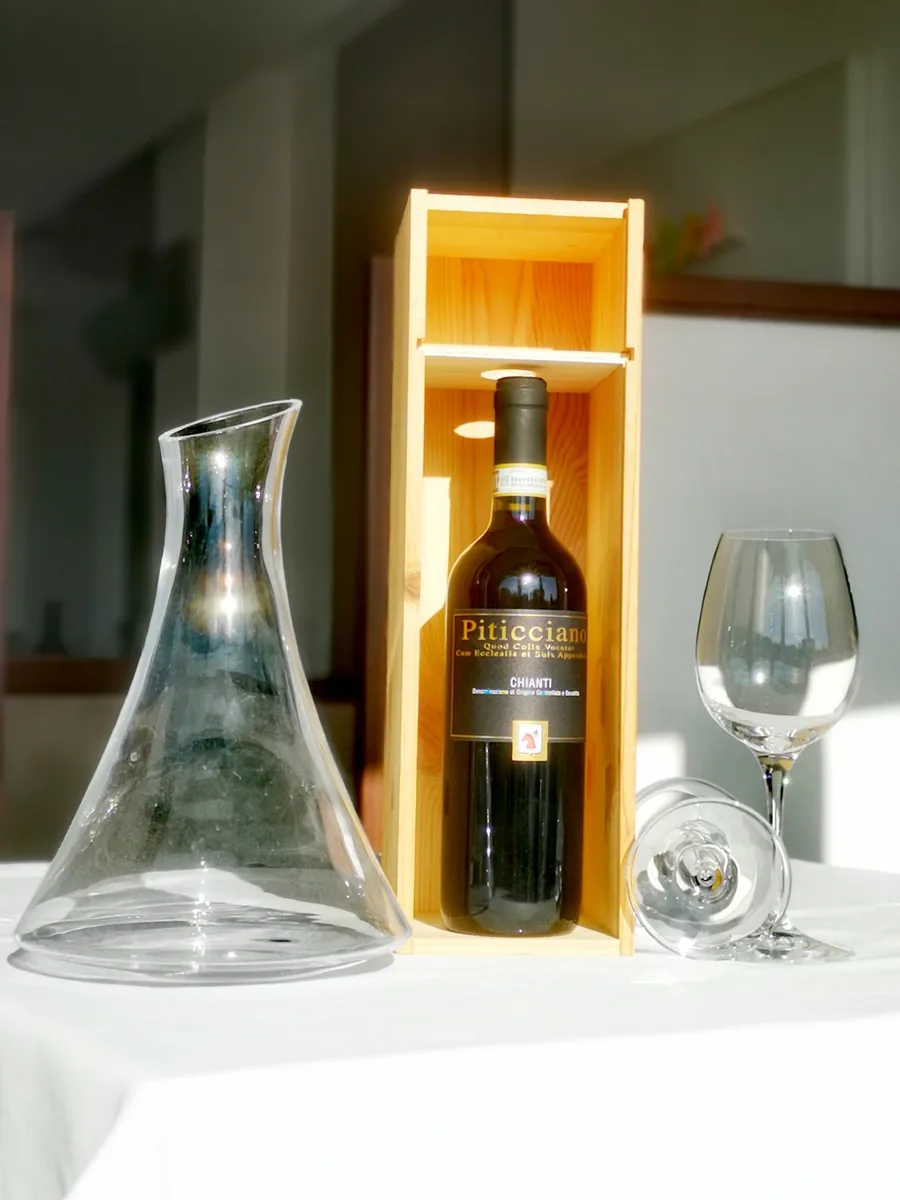 Piticciano Chianti nella cassetta di legno, con decanter e calici alla luce del mattino